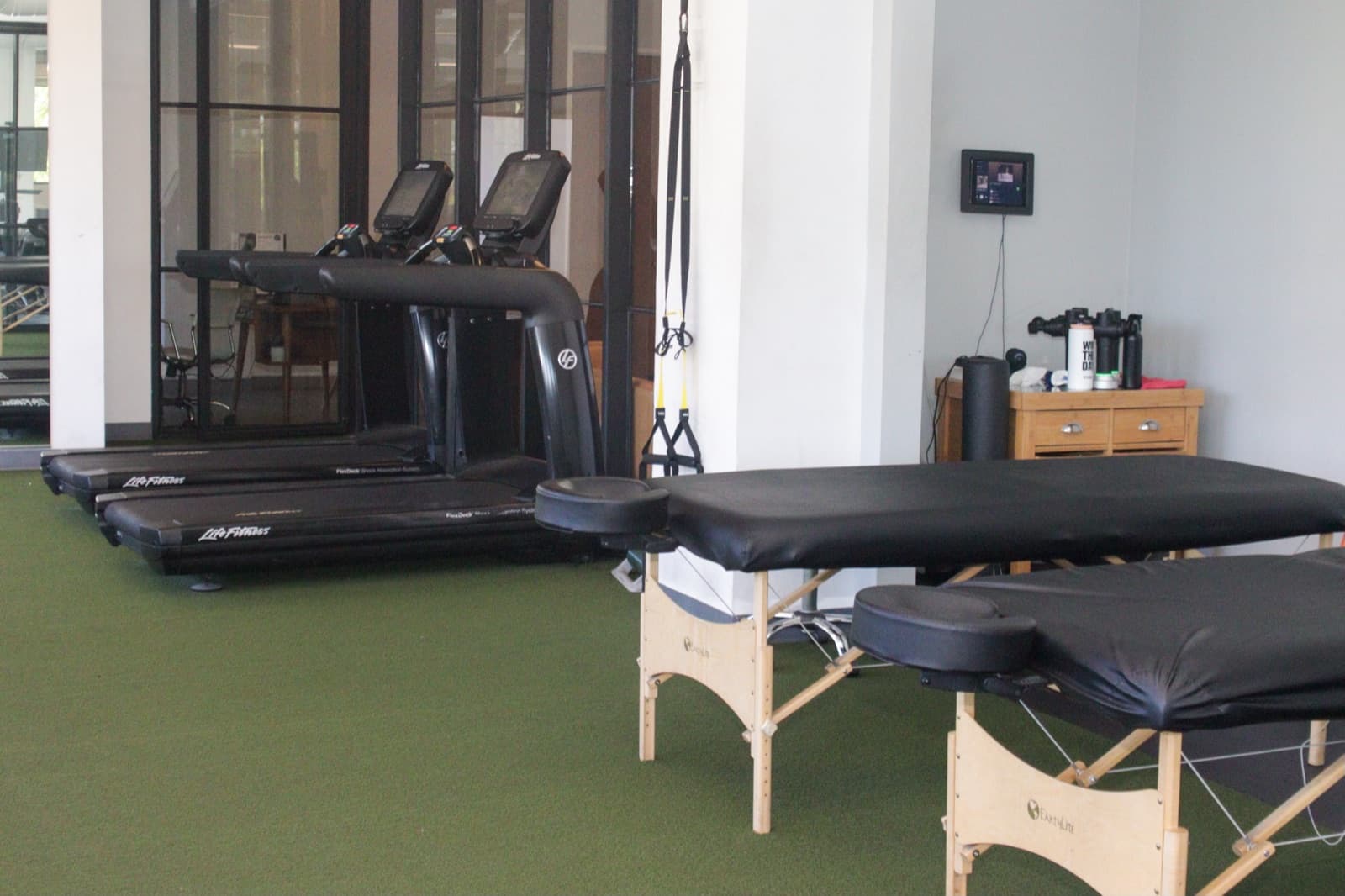 Treatment tables beside cardio equipment inside QiroFit's Los Angeles rehab space.