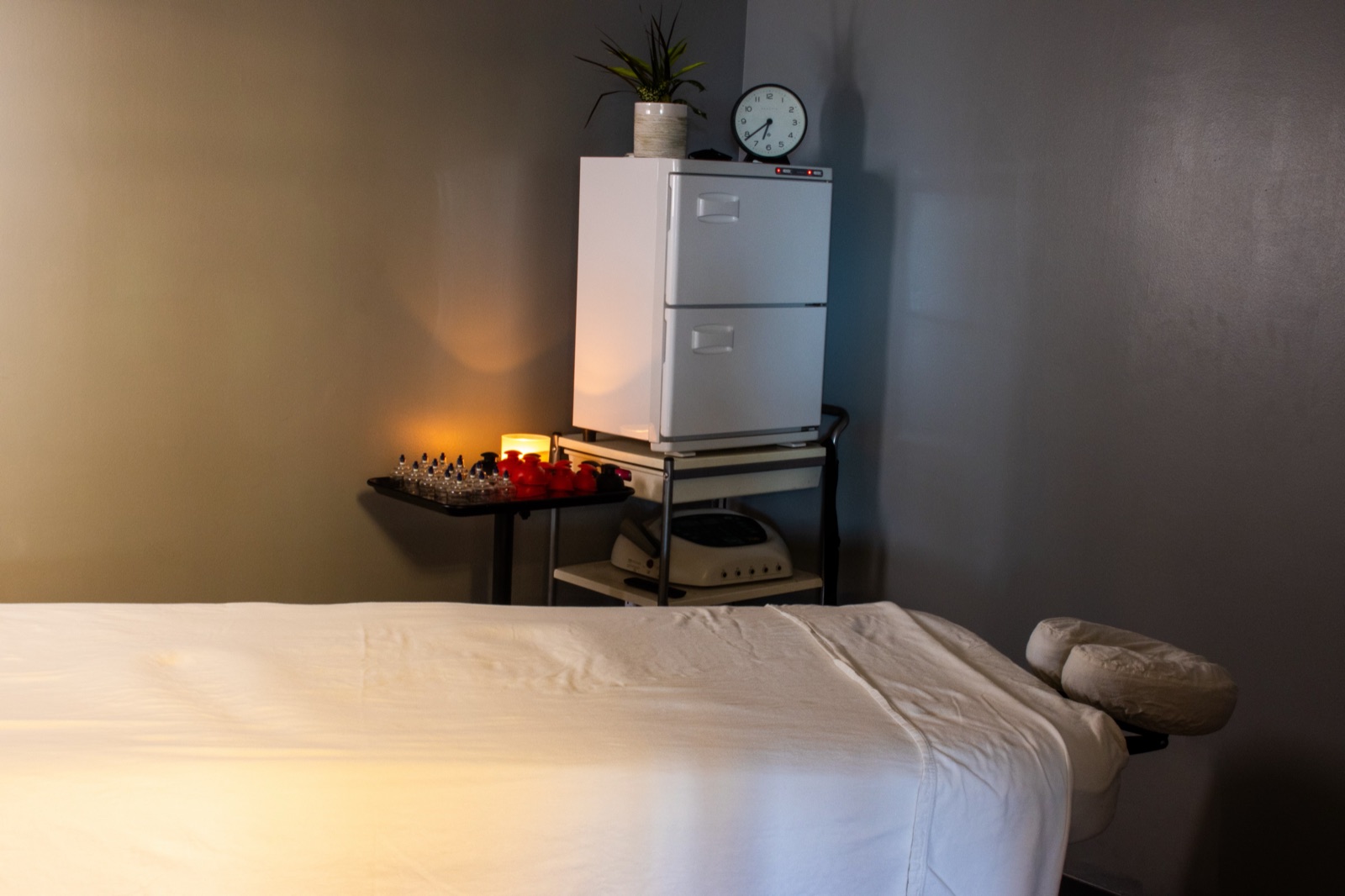 Massage therapy room with a massage table, towel warmer, and cupping set
