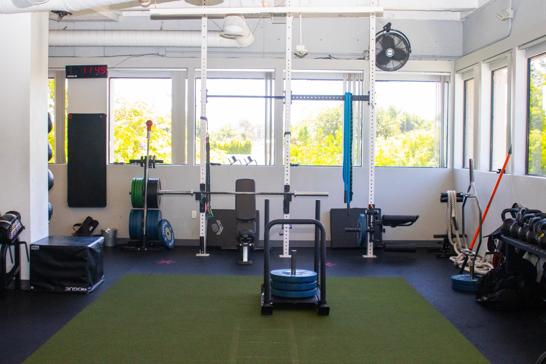 The QiroFit training floor in Los Angeles with a squat rack, weight sled, turf, and conditioning equipment